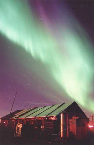 northern lights over glowing cabin
